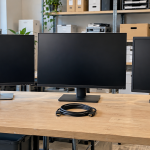 Retired flat-panel monitors and coiled display cables on an office workbench