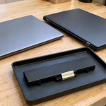 Closed laptops beside an intact removable battery pack on a workbench