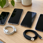 Old smartphones with dark screens and charging cables on an office table