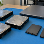 Hard disk drives and solid-state drives arranged beside a closed laptop