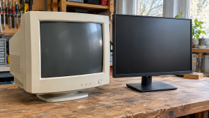 A bulky CRT monitor beside a slim flat-panel monitor on a wooden workbench