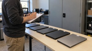 Staff member checking retired computer inventory beside a storage cabinet
